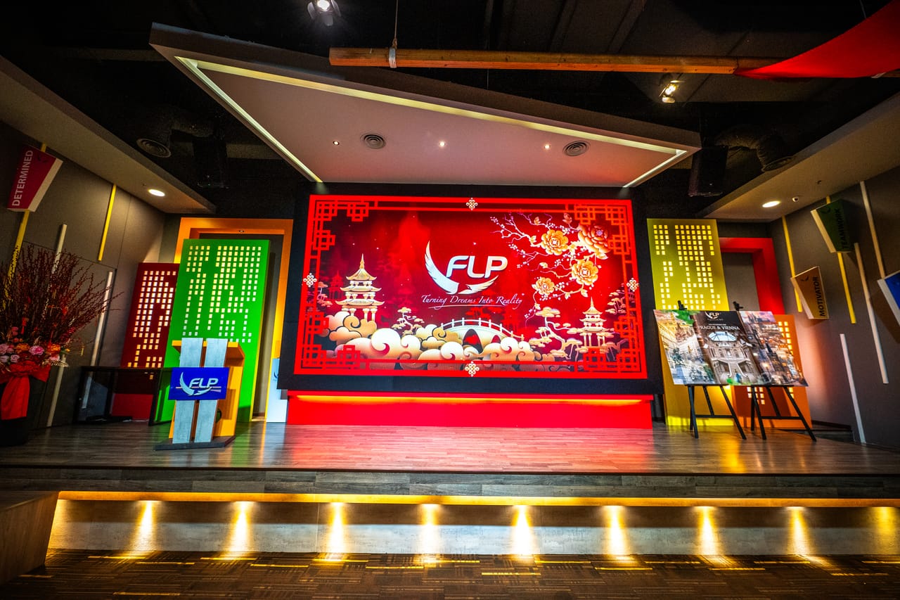 FLP Realty 总部讲堂的舞台，红色大屏幕与台阶灯，二〇二六年新春。